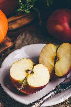 Two Halves of Red Apple on White Plate with Vintage Knife in Rustic Setting