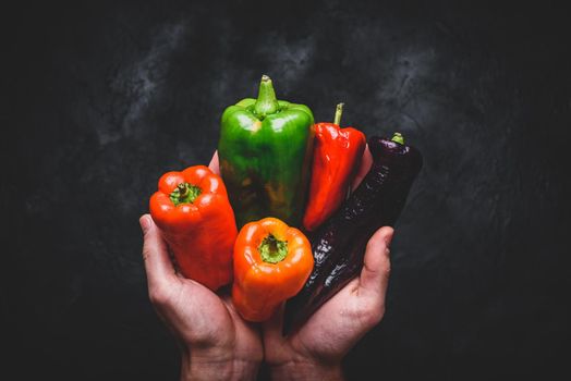 Hands with different bell peppers. View from above