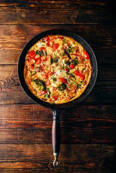 Vegetable frittata with broccoli, red bell pepper and red onion in cast iron skillet. View from above