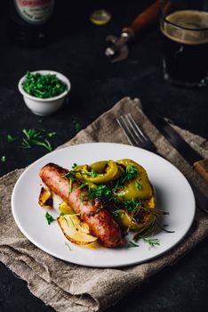 Pork sausage baked with bell peppers, onions and different herbs on white plate