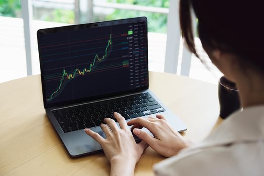 New normal, self-employed women are using a computer laptop to trade stocks for profit, buying and selling.