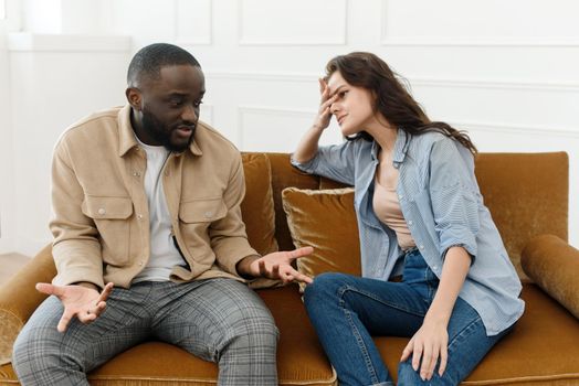 Stressed unhappy millennial Caucasian and African American couple have relationship problems. Diverse couple fighting while visiting professional psychologist for help, breakup prevention concept