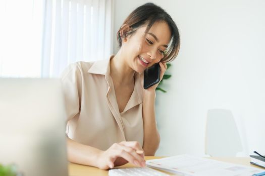 new normal, a businesswoman using computer and smartphone to work for a company Via the internet on your desk at home