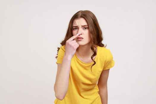 You are liar. Portrait of angry beautiful brown haired young woman in casual style clothing standing and looking at camera with lie sign. Indoor studio shot isolated on gray background.