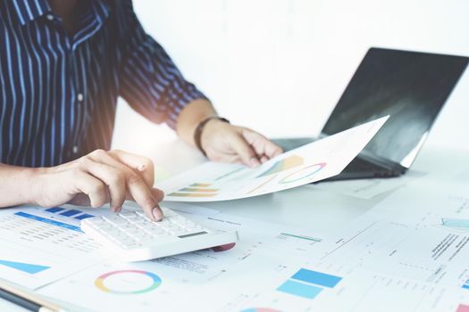 businessman hands using a calculator to check company finances and earnings and budget. calculating monthly expenses, managing budget, papers, loan documents, invoices concepts.