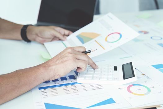 businessman hands using a calculator to check company finances and earnings and budget. calculating monthly expenses, managing budget, papers, loan documents, invoices concepts.