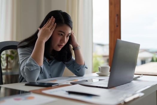 Image of Asian Business woman stressed while analyzing financial report balance. Financial and investment concept