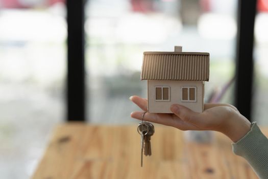 Close up Business woman or Real Estate agent giving house key after signing agreement for buying house. Bank manager and real estate concept