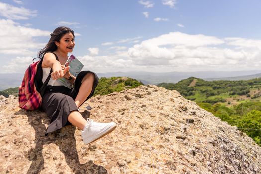 Female university student from Nicaragua smiling happy with thumb up sitting on a rock outdoors