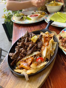 Meat with cabbage in a pan on a stand stands on a table in a restaurant. High quality photo