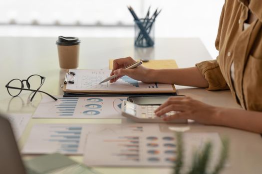 Close up Business woman hand using calculator to calculate the company's financial results and budget. Account Audit Concept