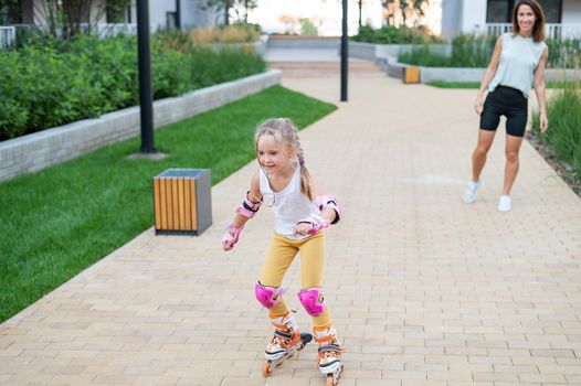 Caucasian woman teaches her daughter to skate on roller skates