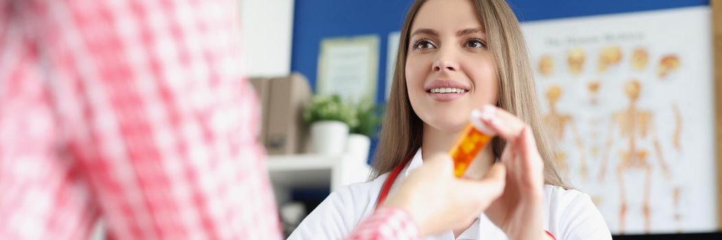 Portrait of qualified female doctor give medications in bottle to patient for faster recovery. Woman on appointment get advice from nurse. Medicine concept