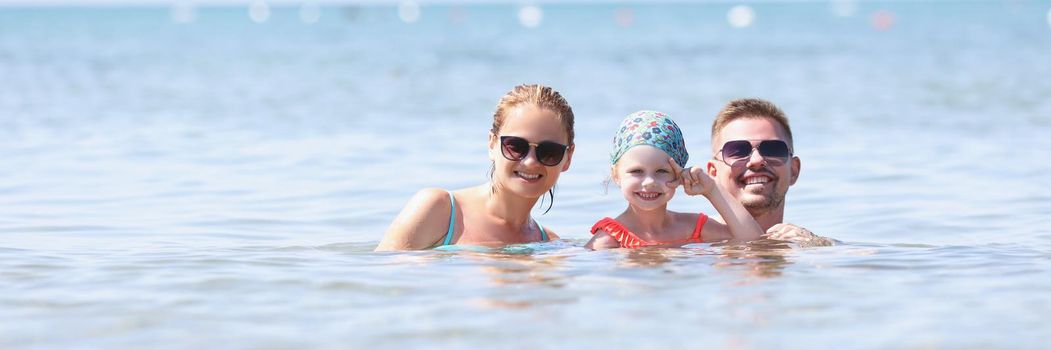 Portrait of happy family posing for picture together in sea or ocean. Memorable vacation together, family holiday, quality time. Summer, trip, joy concept