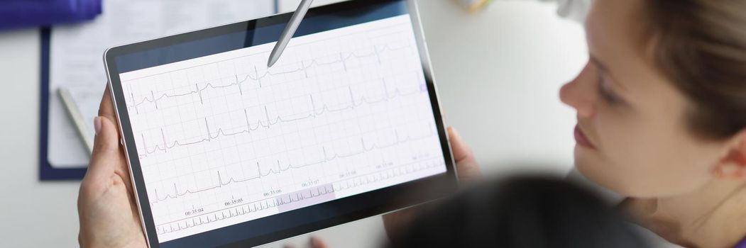 Close-up of doctor show digital tablet screen with heart cardiogram result to coworker. Examination of cardiovascular system. Medicine, cardiology concept