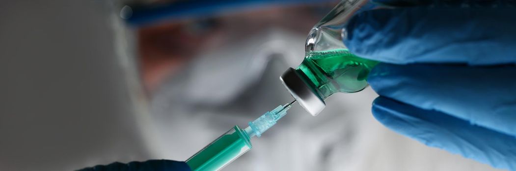 Close-up of scientist holding injection needle in hands in blue gloves. Dose of chemical substance in laboratory. Vaccination, analysis, test, lab concept