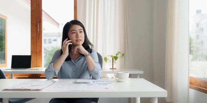 Portrait of Asian Business woman at work talking on phone. Finance Concept