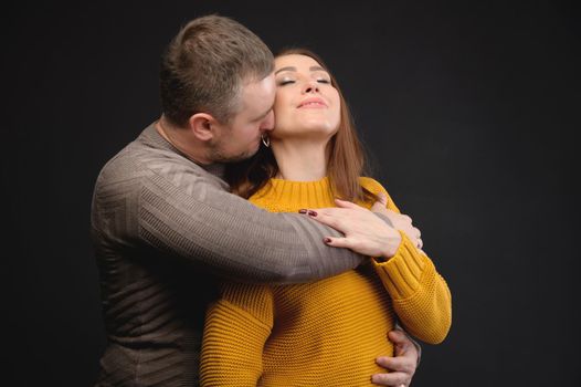 Cute couple in love kissing and hugging in the studio on a black background.