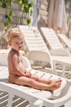 Little girl sits on a sun lounger. High quality photo
