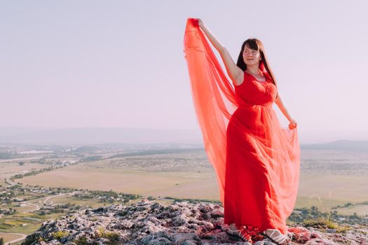 A girl in a red dress on the background of the mountains lifestyle. Illustrating articles about travel. A girl with a beautiful view. Vacation in Crimea. White rock. View of the villages. Lifestyle processing. Copy space .