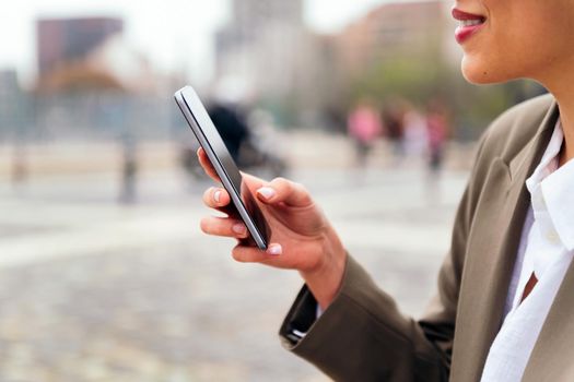 close up of the hand of an unrecognizable woman using a mobile phone outdoors, concept of communication and urban lifestyle, copy space for text