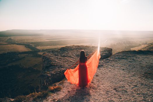 A girl in a red dress on the background of the mountains lifestyle. Illustrating articles about travel. A girl with a beautiful view. Vacation in Crimea. White rock. View of the villages. Lifestyle processing. Copy space .