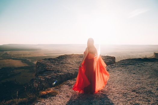 A girl in a red dress on the background of the mountains lifestyle. Illustrating articles about travel. A girl with a beautiful view. Vacation in Crimea. White rock. View of the villages. Lifestyle processing. Copy space .