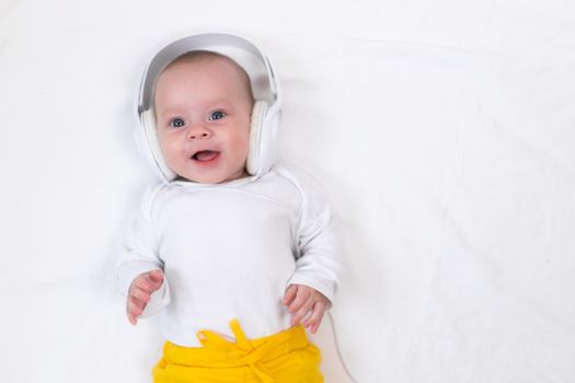 The kid listens to music with headphones on a white background. An article about children. Music for children. The benefits of classical music for children. Article about headphones. The choice of headphones. Copy Space