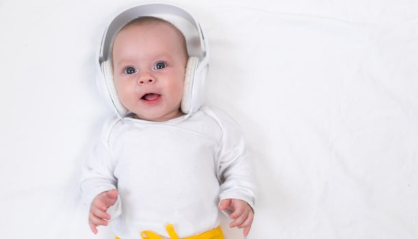 The kid listens to music with headphones on a white background. An article about children. Music for children. The benefits of classical music for children. Article about headphones. The choice of headphones. Copy Space