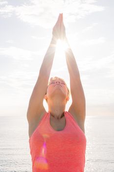 vertical photo of a woman meditating and practicing yoga at sunrise in front of the sea, concept of mental health care and relaxation, copy space for text