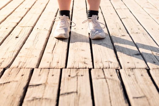 feet of an unrecognizable runner with running shoes on a wooden floor, concept of sport and healthy lifestyle, copy space for text