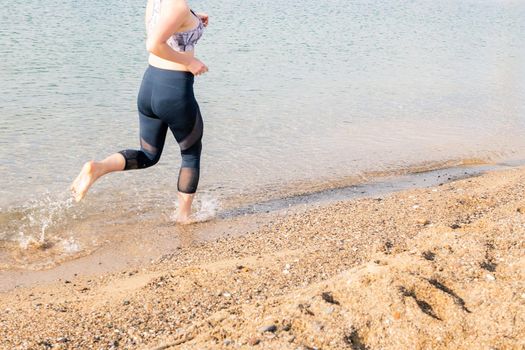 unrecognizable sportswoman running along the beach, healthy lifestyle and sports concept, text copy space