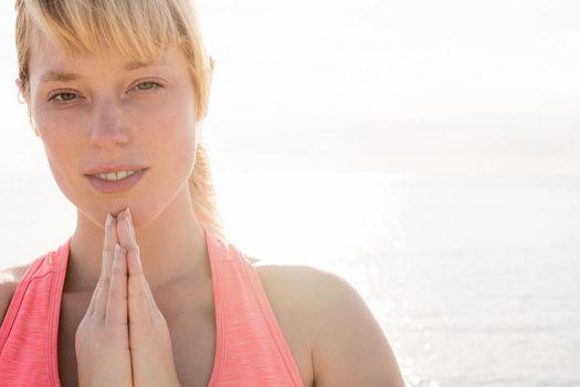 portrait of a beautiful blonde woman meditating and practicing yoga at sunrise in front of the sea, concept of mental health care and relaxation, copy space for text