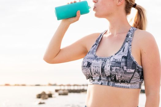 unrecognizable blonde sports woman drinking water from a bottle, healthy lifestyle and sports concept, copy space for text