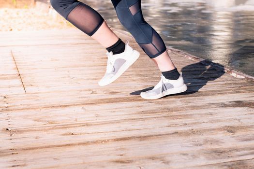 unrecognizable female runner legs jogging in running shoes on a wooden floor, sport concept and healthy lifestyle, copy space for text