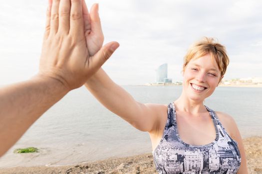 portrait of a smiling blonde sportswoman high five with her partner, concept of healthy lifestyle and sport, copy space for text