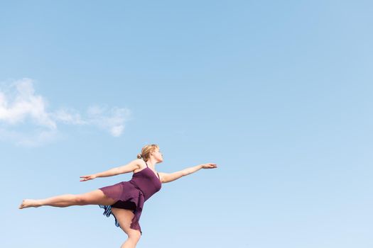 young blonde ballet dancer dancing with the sky in the background, concept of freedom and dance, copy space for text