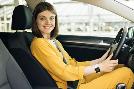 Portrait of young woman fasten seat belt in her car. Protection of female person in vehicles. Road safety regulations concept.