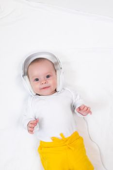 The kid listens to music with headphones on a white background. An article about children. Music for children. The benefits of classical music for children. Article about headphones. The choice of headphones. Copy Space