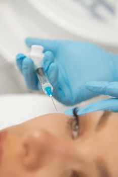 Vertical close up of a professional cosmetologist performing botox facial injections for her client. Woman getting filler injections under eyes rejuvenation youth beauty cosmetology plastic surgery