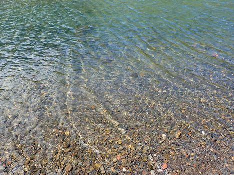 Crystal clear water of tropical waters with rocks visible through water.