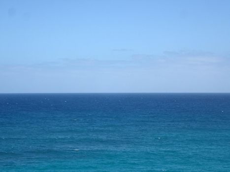 Shallow wavy ocean waters of Waimanalo bay looking into the pacific ocean with a blue sky full of clouds on Oahu.