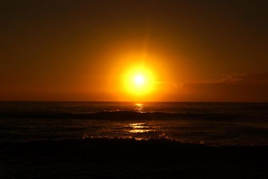 Spectacular Sunrise over the ocean with waves crashing along shore in Hana on Maui, Hawaii.                               