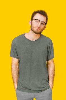 Handsome young man in casual wear and eye glasses posing on yellow background. Stylish bearded smart casual look hipster man. Thoughtful guy on yellow background.