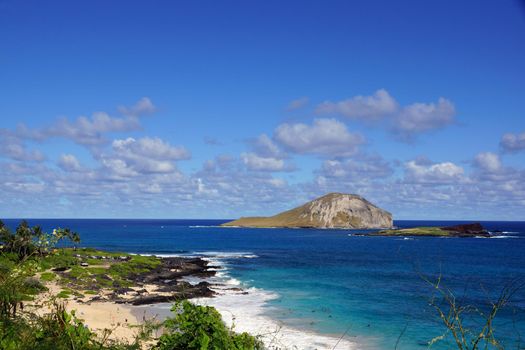 Makapuu beach with people in the water, and Rabbit and Rock Island in the distance on Oahu, Hawaii.