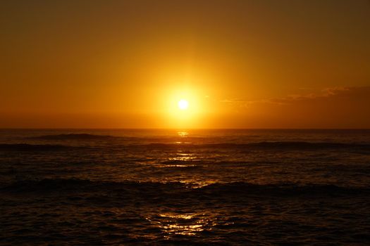 Spectacular Sunrise over the ocean with waves rolling toward shore in Hana on Maui, Hawaii.   