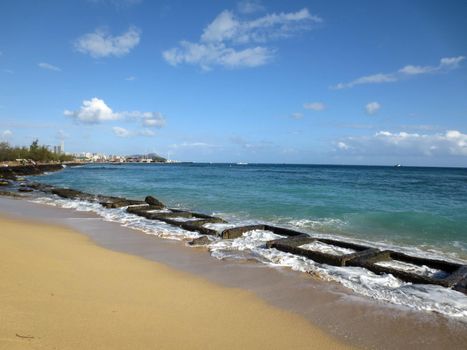 Old military water break on Sand Island Beach with tugboat on horizon and downtown Honolulu in the distance on Oahu, Hawaii