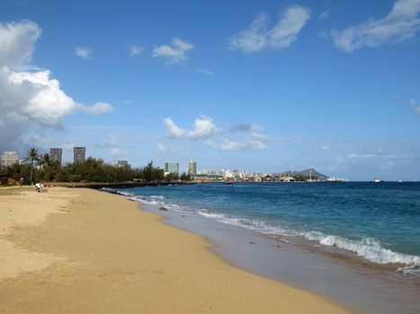 Sand Island Beach with Downtown Honolulu, Diamond head Crater in the distance on Oahu, Hawaii and tugboat in the water.