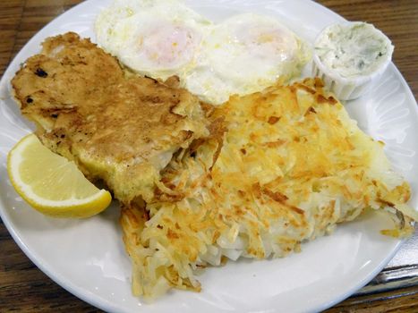 Breaded and fried BREAKFAST Mahi Mahi AND With two eggs served with hash brown potatoes, tartar sauce, and lemon slice.
