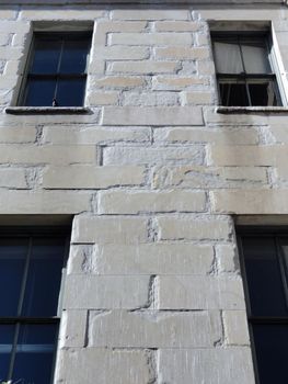 Close-up of side of San Francisco Mint Building with granite wall and windows with bird in window edge. the Old United States Mint, also known affectionately as The Granite Lady, is one of the few that survived the great 1906 San Francisco earthquake.                                